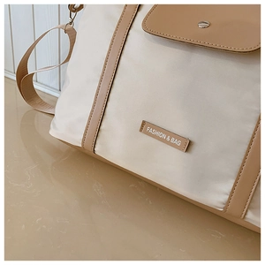 Detailed shot of beige nylon handbag with light brown trim and decorative brand tag