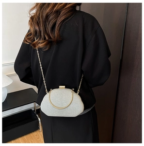 Model wearing a glittering silver evening clutch with gold chain strap on black outfit