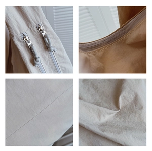 Detail view of khaki shoulder bag showing dual zippers and premium fabric texture