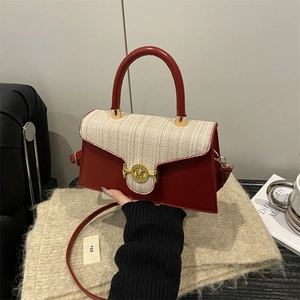 Rote Leder- und beige Tweed-Umhängetasche mit goldenem M-Schloss auf Strickhintergrund