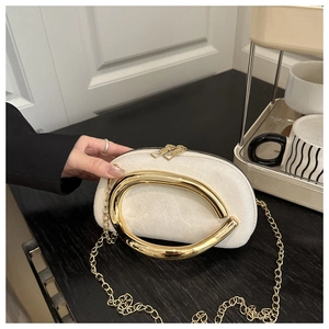 Vue détaillée du sac rond en velours blanc avec poignée en C dorée et bandoulière chaîne