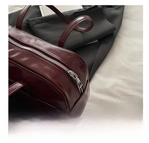 Detailed close-up of the smooth silver metal zipper on a dark red leather tote bag