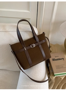 Détail du sac texturé marron foncé avec boucle argentée sur un canapé beige chic
