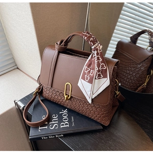 Close-up of brown woven leather handbag with gold U-buckle and floral silk scarf detail