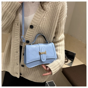 Detail view of light blue quilted crossbody bag with golden H clasp on a person