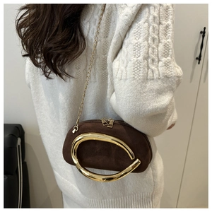 Détail d'une pochette en daim marron avec poignée dorée géante sur un pull en maille beige