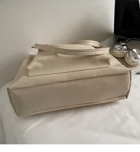 Detail of a large beige PU leather tote bag in a casual office setting with a laptop