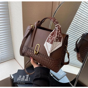 Detail of a brown leather tote with woven texture, U-shaped gold buckle and silk scarf