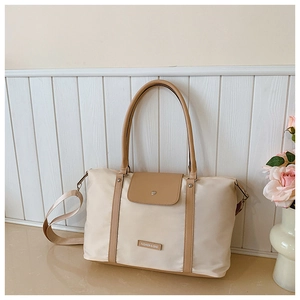 Detail of beige nylon tote bag with brown leather trim and FASHION & BAG lettering