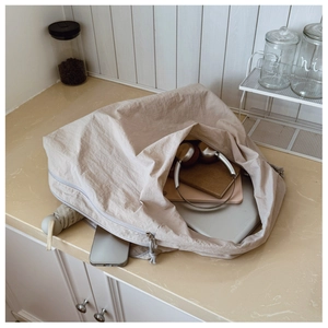 Spacious beige nylon hobo bag showing large storage capacity for laptop and daily essentials