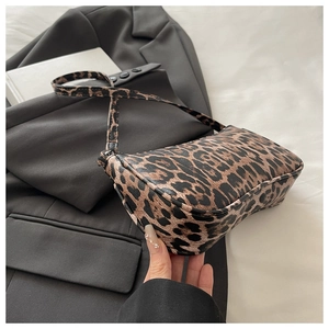 Detailed view of leopard print baguette bag on a grey blazer with fashion accessories