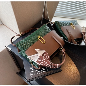 Detail of green woven leather handbag with gold U-shaped buckle and silk scarf handle