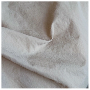 Macro detail of beige woven linen fabric texture and natural pleated folds on a tote bag