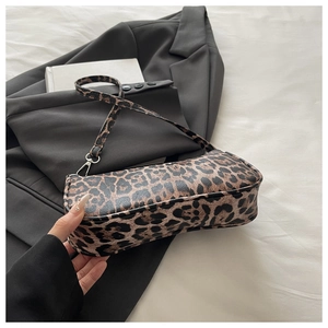 Detail of trendy leopard print baguette bag featuring smooth PU leather and silver hooks