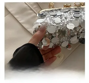 Detail of silver sequin evening bag with gold floral embossed metal clasp and chain