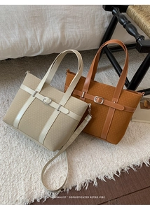 Retro minimalist bucket bags in beige and tan leather with silver buckles on white rug
