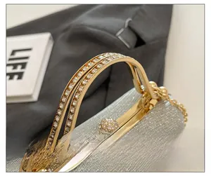 Detailed close-up of a silver clutch with gold rhinestone-studded handle and metal buckle