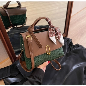 Detail of dark green woven texture handbag with silk scarf handle on black satin