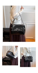 Détail d'un grand sac bandoulière en cuir froissé noir brillant avec bandoulière chaîne