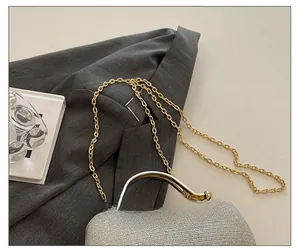 Detail of silver sequin evening bag featuring gold chain strap and metal handle