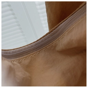 Detailed close-up of khaki shoulder bag zipper closure with high-quality stitching