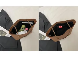 Detail view of the large capacity interior of a brown tote bag with zipper pocket and chain