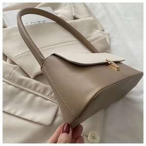 Détail du fermoir doré et des coutures sur le sac à main bicolore beige et crème