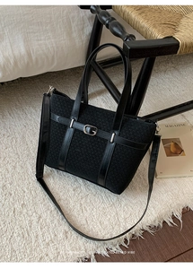 Détail du cabas en maille noire avec boucle argentée sur un tapis blanc doux et élégant