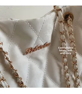 Detail of creamy white quilted shoulder bag showing soft fabric and golden chain strap