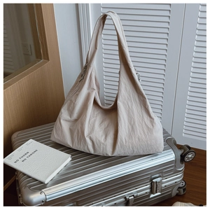 Detail of a large beige tote bag with pleated fabric on a silver travel suitcase