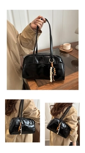 Detail of glossy black shoulder bag with beaded charm and high-shine patent finish