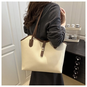 Detail of lychee pattern leather tote bag in beige and brown with golden metal buckle