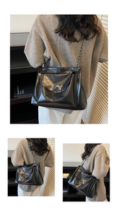 Detail view of large black tote bag with silver bow buckle and chain strap