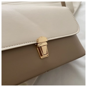Gros plan du fermoir en métal doré et des coutures contrastées du sac à main chic