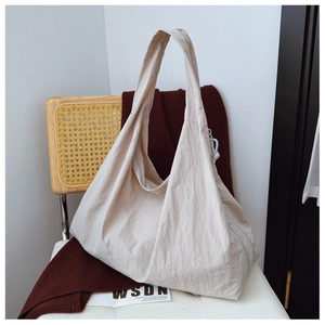 Detail of minimalist beige nylon tote bag with wide strap and drawstring on a chair