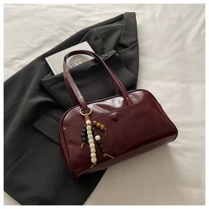 Deep burgundy tote bag detail with vintage leather texture and colorful beaded wooden charm