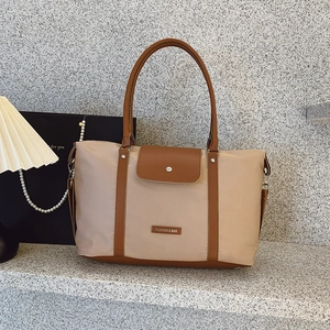 Large beige nylon tote bag with brown leather trim and metal logo for casual travel