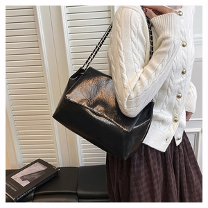 Détail de sac à bandoulière en cuir plissé noir brillant avec chaîne en métal