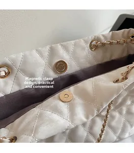 Detail view of the magnetic closure and quilted texture on cream shoulder bag