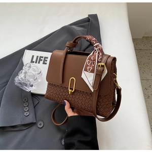 Detail of brown patchwork handbag with woven texture, silk scarf, and gold metal lock