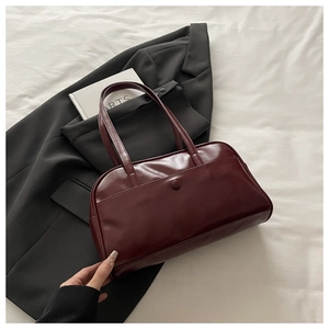 Close-up of a burgundy leather tote bag with elegant front button pocket and double handles