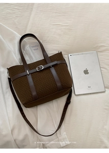 Macro detail of dark brown knit tote bag with faux leather handles and silver metal buckle
