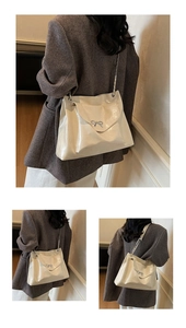 Close-up of cream glossy leather tote featuring silver bow and chain shoulder strap