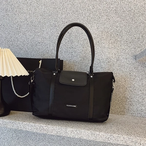 Large black nylon tote bag with leather straps and adjustable shoulder strap for travel