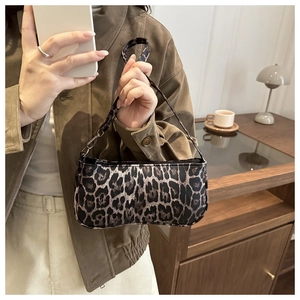 Detail of trendy leopard print shoulder bag with metal buckles and slim handle straps