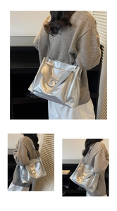 Detail of silver bow metallic tote bag with chain strap and shiny faux leather texture