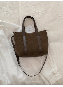 Close-up of brown knitted texture tote bag with leather handles and metallic hook detail