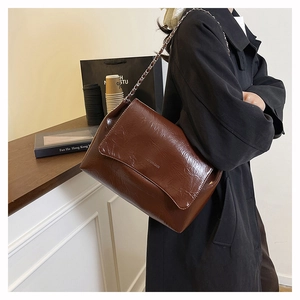 Détail du sac vintage en cuir marron plissé avec chaîne argentée dans une ambiance style de vie