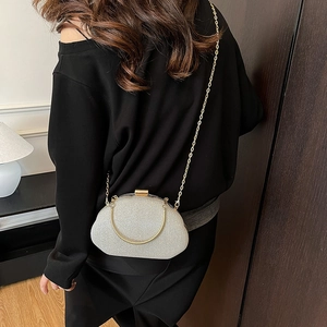 Silver sequin shell evening bag with gold chain strap shown on model in a modern room