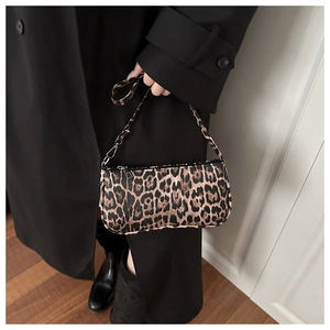 Close-up of leopard print underarm bag with zipper closure and black trench coat